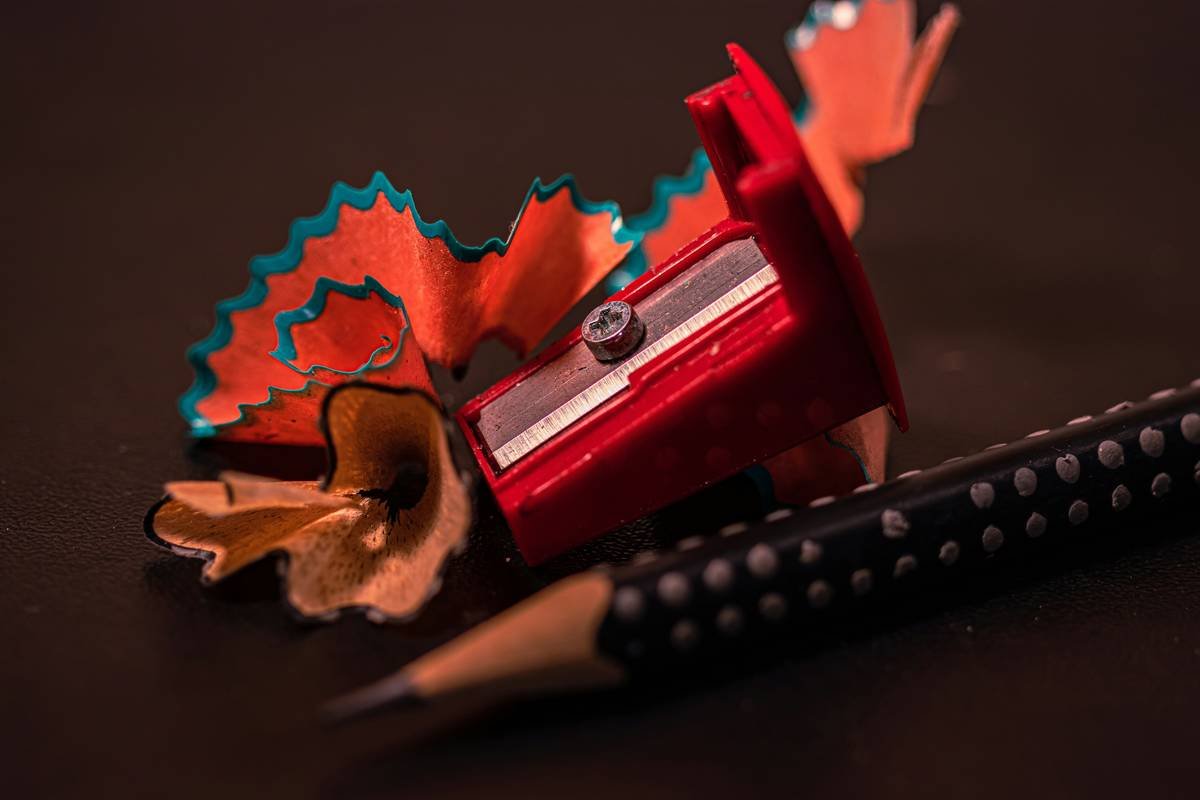Close-up of hand using how to use lip liner sharpener correctly with chilled pencil and dual-blade tool